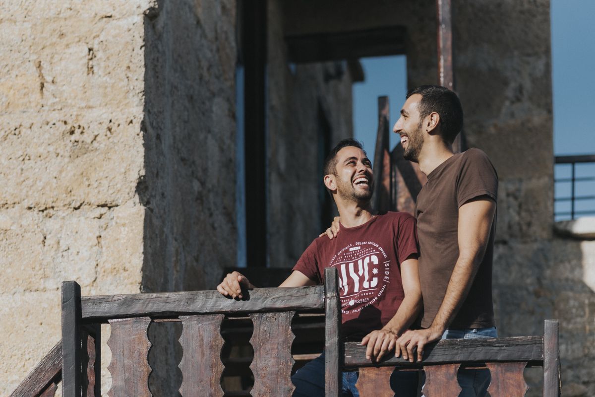 Two men laughing on a wooden balcony in Tenerife.