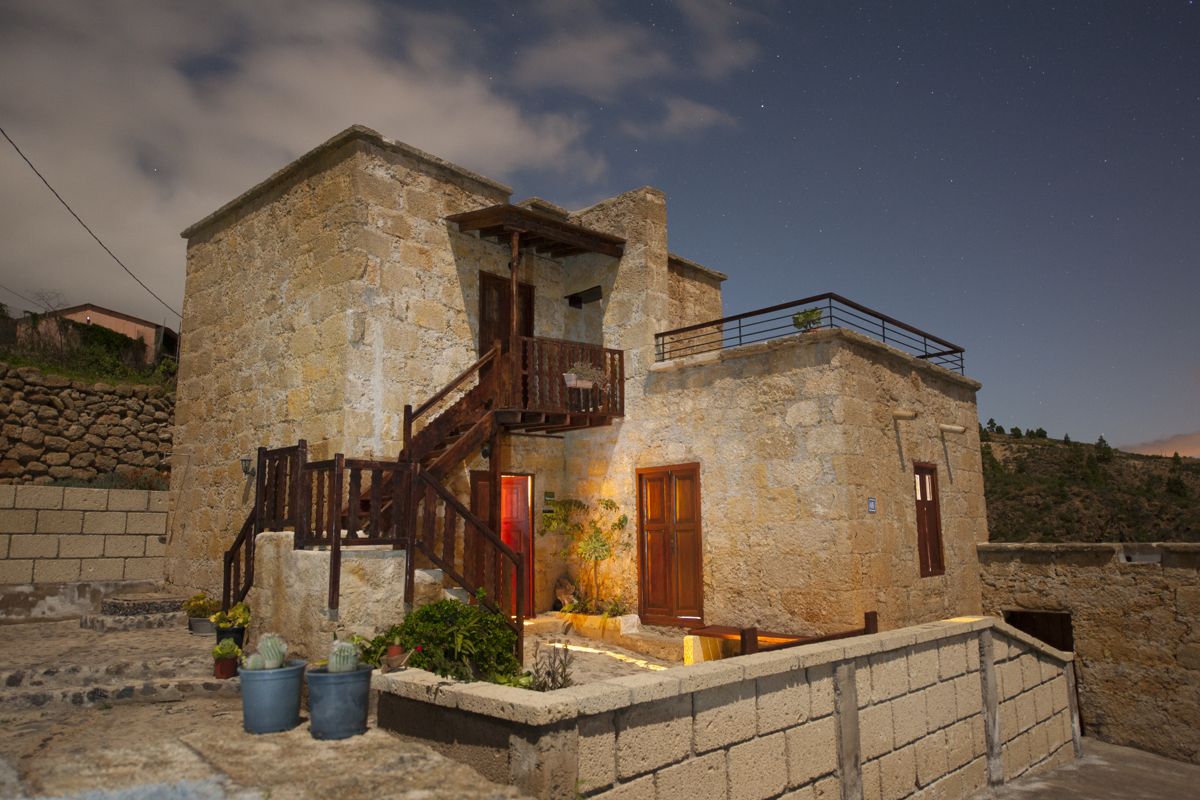 Stone house with wooden stairs and potted plants in Tenerife at night.