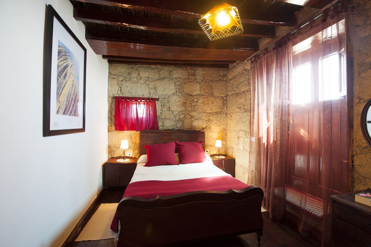 Bedroom with double bed, brick wall, pink curtains in Los Realejos, Tenerife.