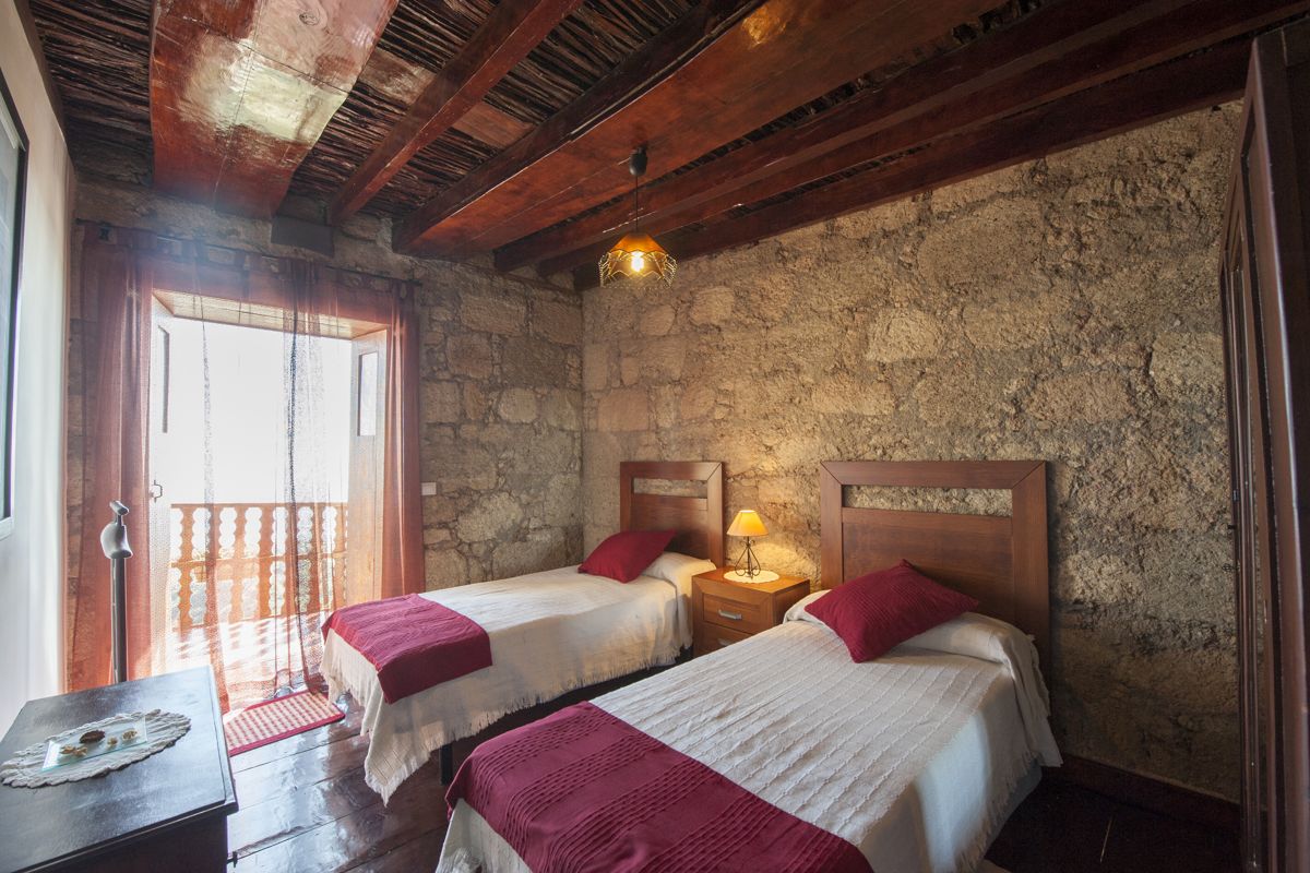 Two single beds with red accents in a rustic room in Tenerife.