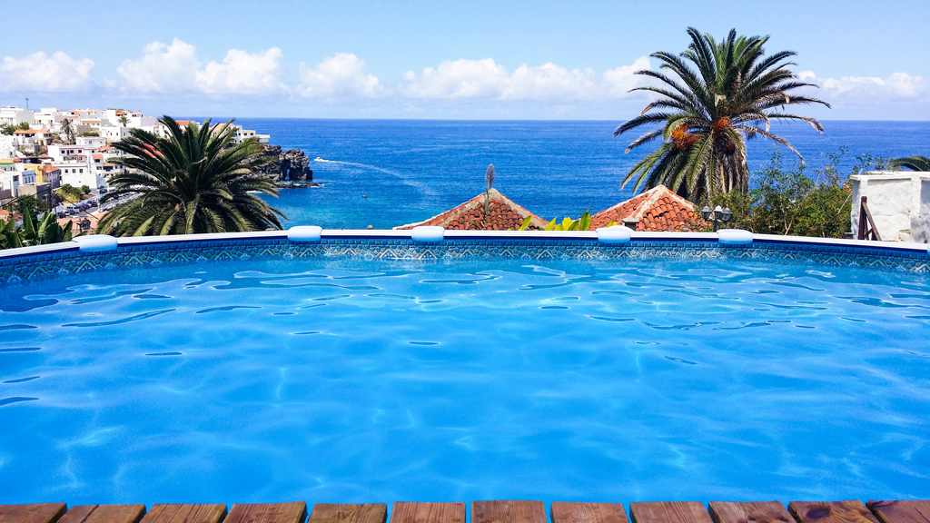 Swimming pool overlooking ocean and palm trees in Tenerife.