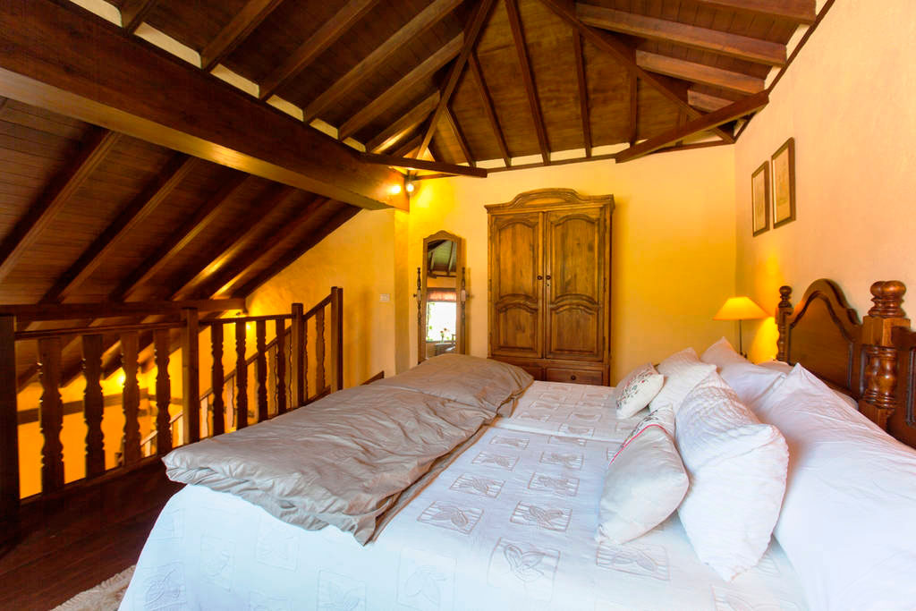 Bedroom with wooden ceiling, bed, wardrobe, and lamp in a Tenerife house.