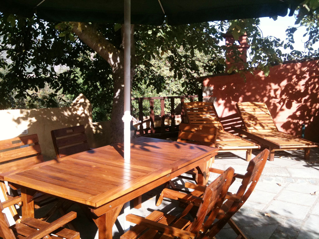 Wooden outdoor furniture and sun loungers under a tree in Tenerife.
