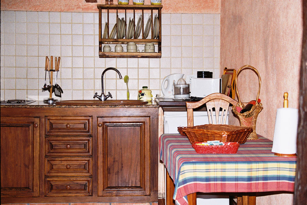 Rustic kitchen with wooden cabinets, table, and tiled backsplash in Tenerife.