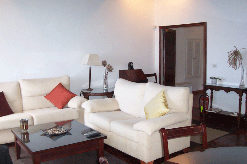 Living room with white sofas, colorful pillows, and a coffee table in Tenerife.