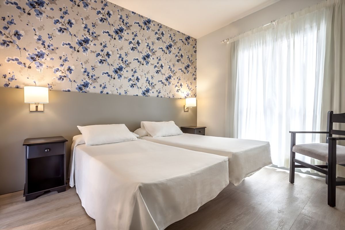 Two single beds in a bright room with floral wallpaper in Tenerife.