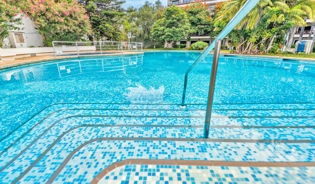 Swimming pool with steps and railing surrounded by trees in Puerto de la Cruz, Tenerife.