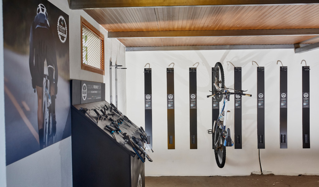 Bike rental station in Tenerife with bikes on hooks and cycling posters.