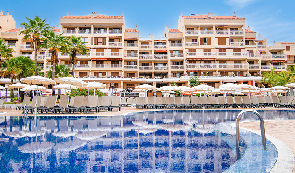 Outdoor pool with lounge chairs and umbrellas at hotel in Tenerife.