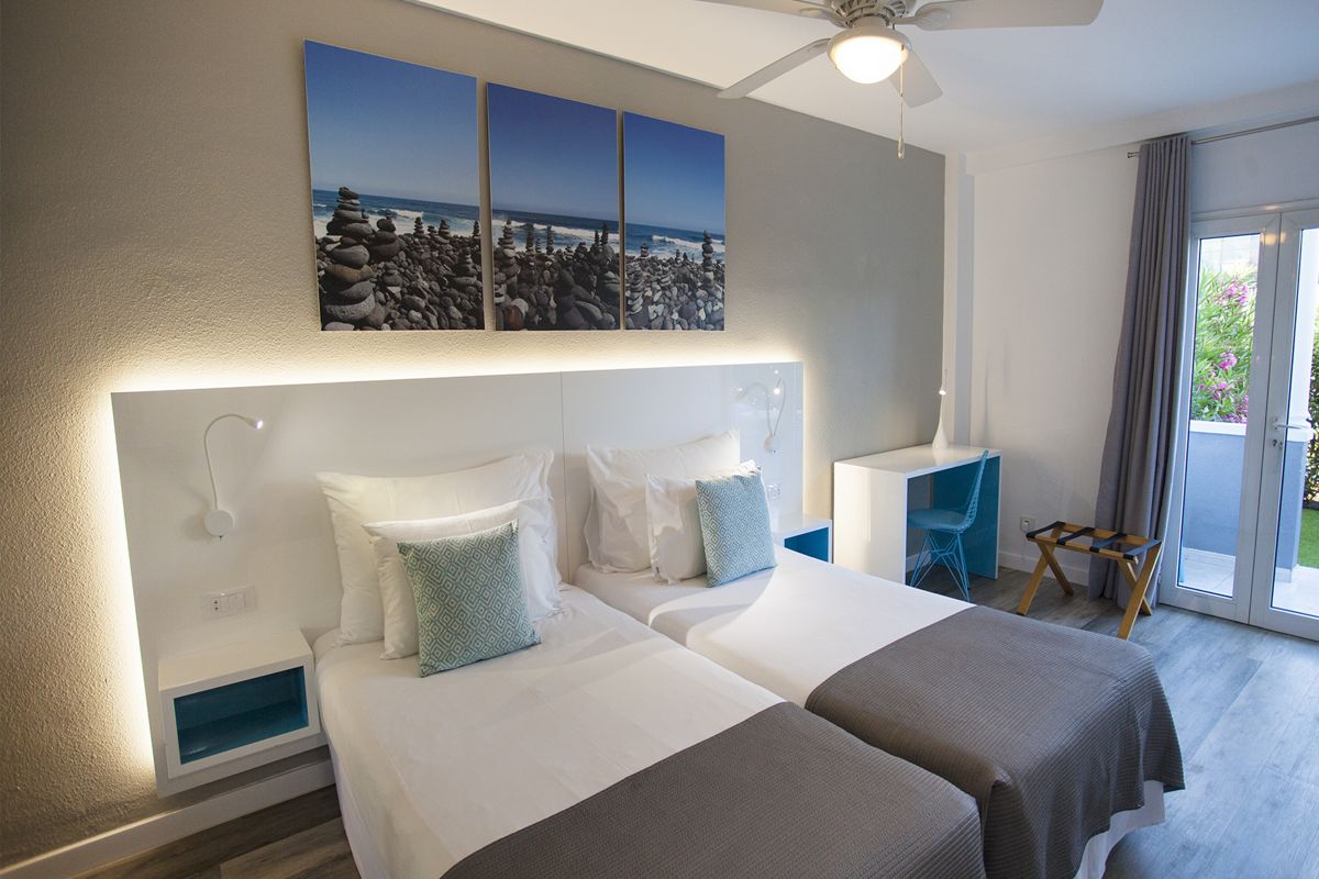 Two single beds in a Tenerife hotel room, decorated with ocean-themed artwork.