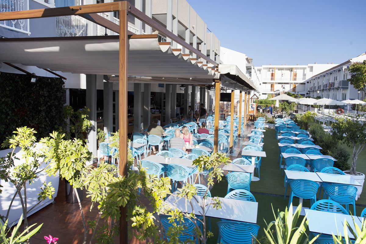 Outdoor dining area in Tenerife with blue chairs and tables under a pergola.