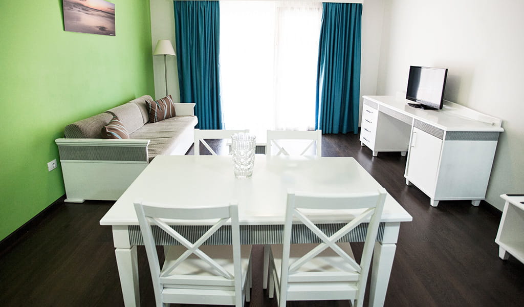 Living room in a Tenerife apartment with white furniture and green walls.