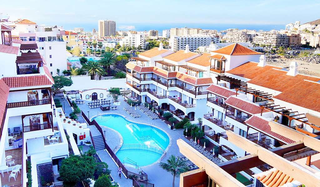 View of a hotel with a pool and surrounding buildings in Tenerife.