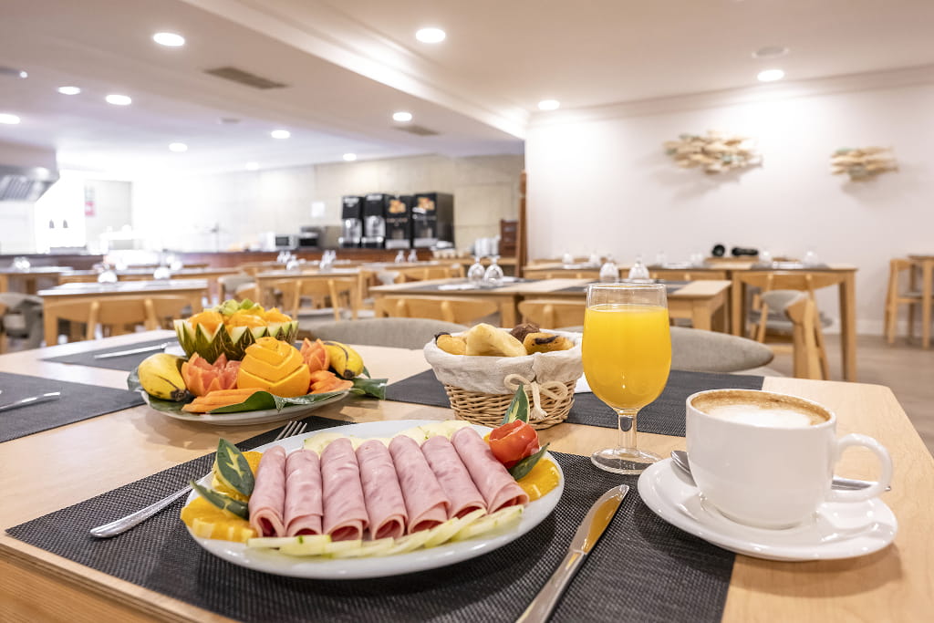 Breakfast spread with ham, fruit, bread, orange juice, and coffee in a Tenerife restaurant.
