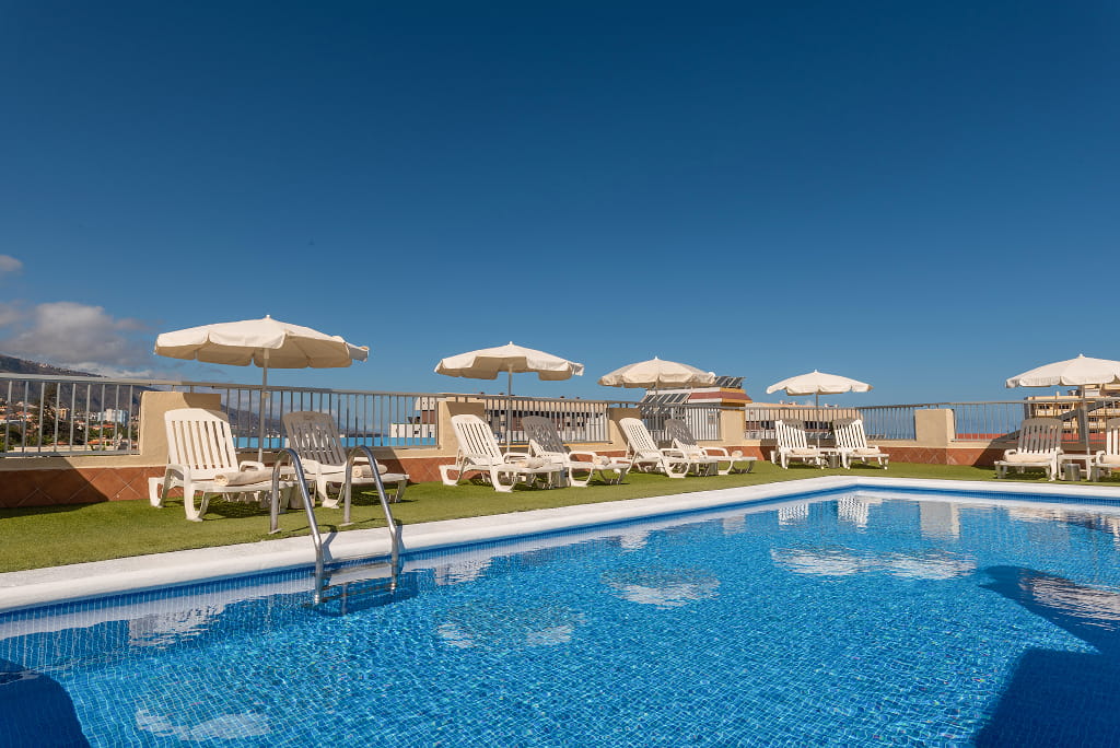 Rooftop pool with lounge chairs and umbrellas in Puerto de la Cruz, Tenerife.