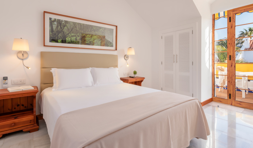 Hotel room with a double bed, two nightstands, and a balcony view in Tenerife.