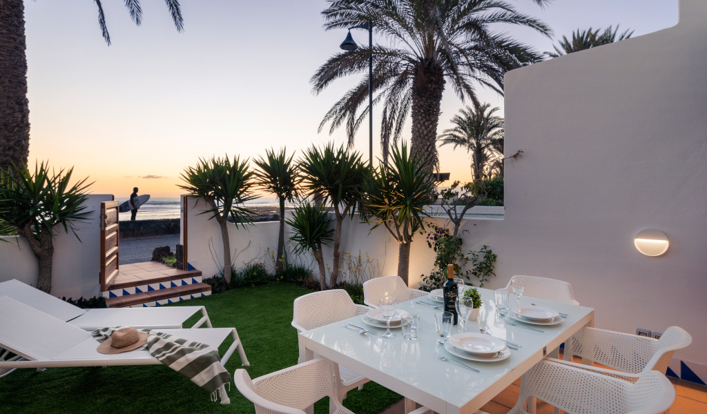 Patio with dining table, chairs, and view of sunset near the beach in Tenerife.