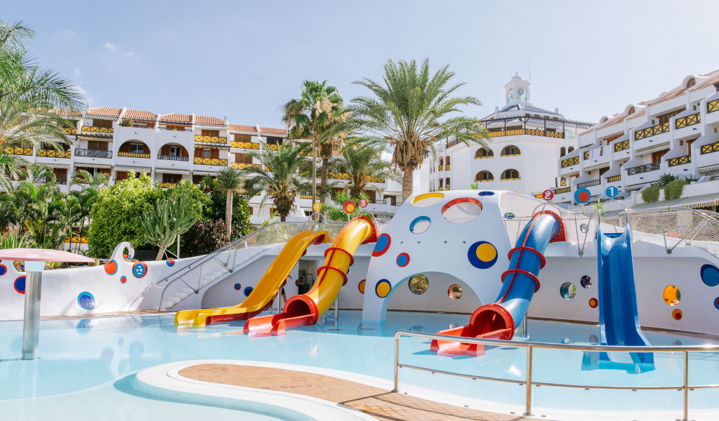 Water park with colorful slides and pool, surrounded by white buildings in Tenerife.