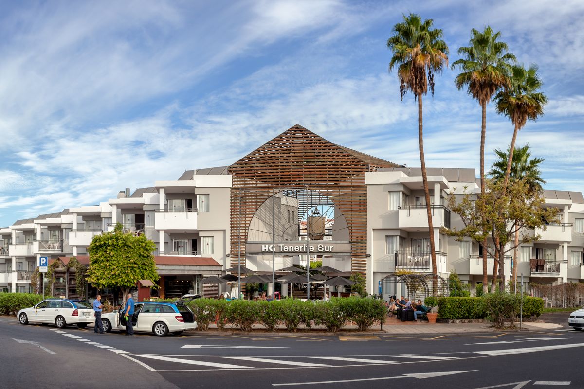 HC Tenerife Sur hotel with palm trees and parked cars in front.