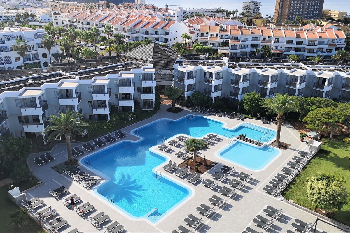 Outdoor pool area surrounded by lounge chairs in Tenerife resort.