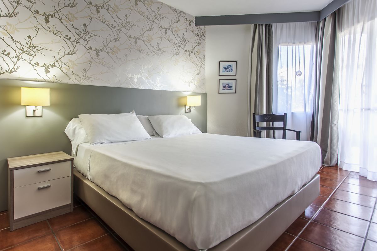 Double bed in a hotel room with nightstand and chair in Tenerife.