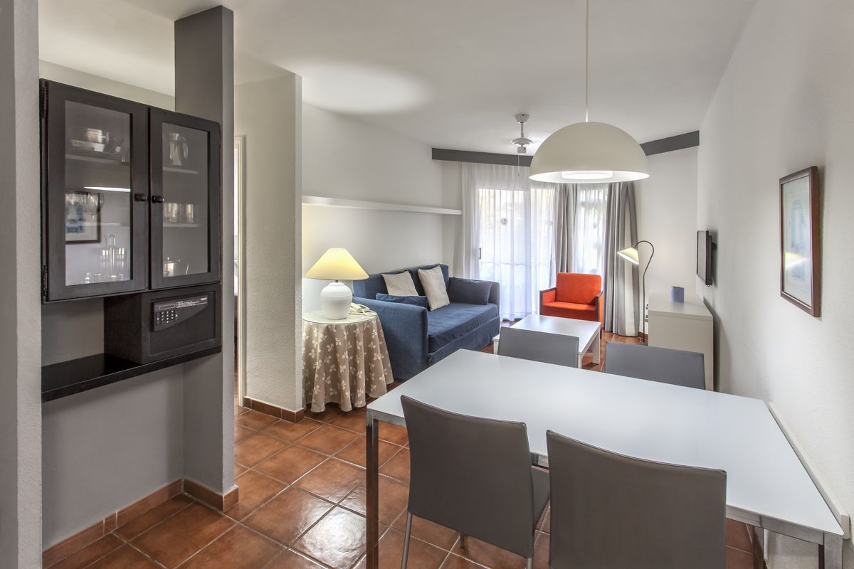 Living room with sofa, armchair, dining table, and lamp in a Tenerife apartment.