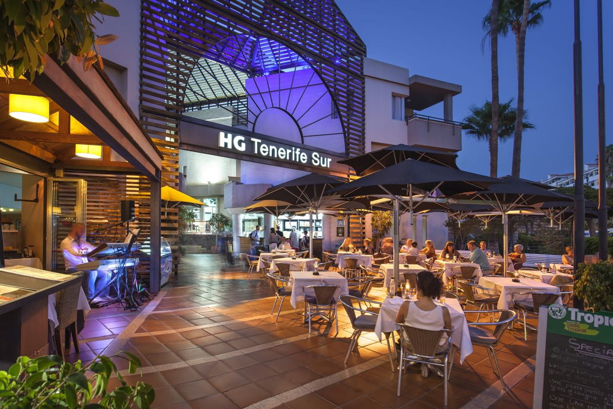 Outdoor dining area at HG Tenerife Sur with people seated at tables in the evening.