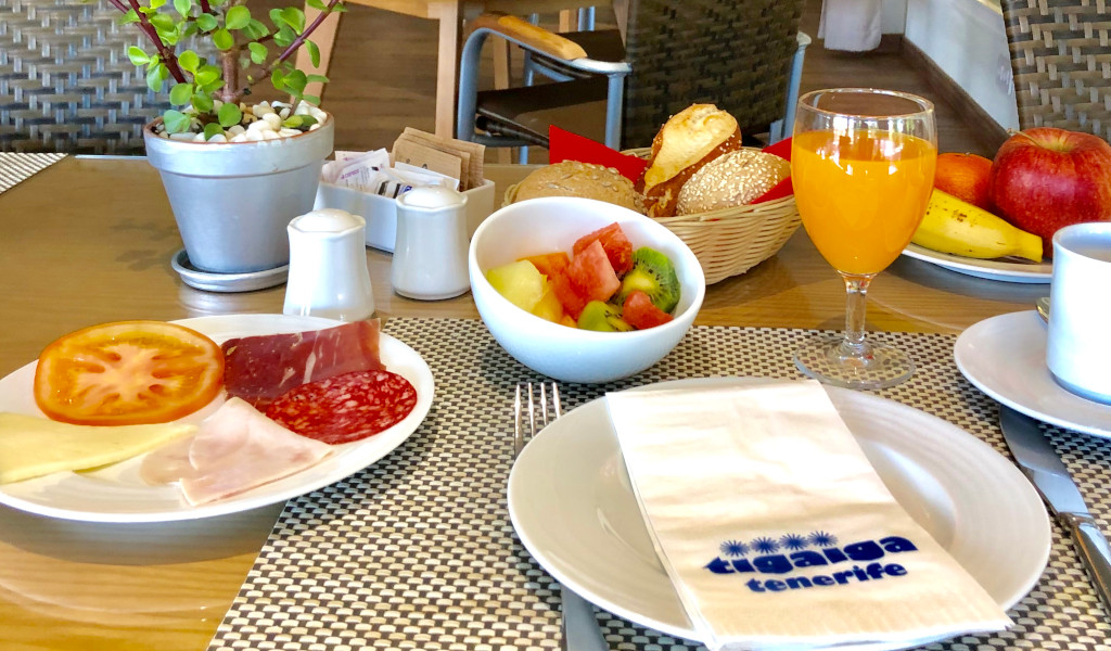Breakfast with fruit, cold cuts, bread, orange juice, and napkin labeled Tigaiga Tenerife.