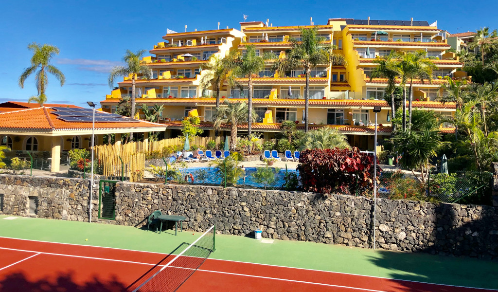 Resort with palm trees and a pool near a tennis court in Tenerife.