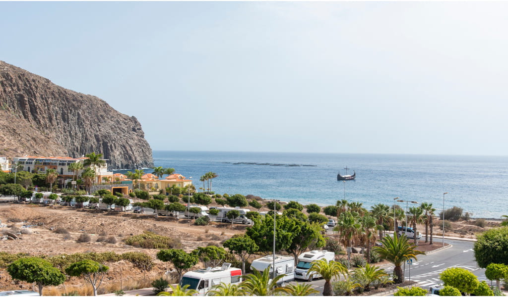 Coastal view of a ship near the cliffs and buildings in Tenerife.