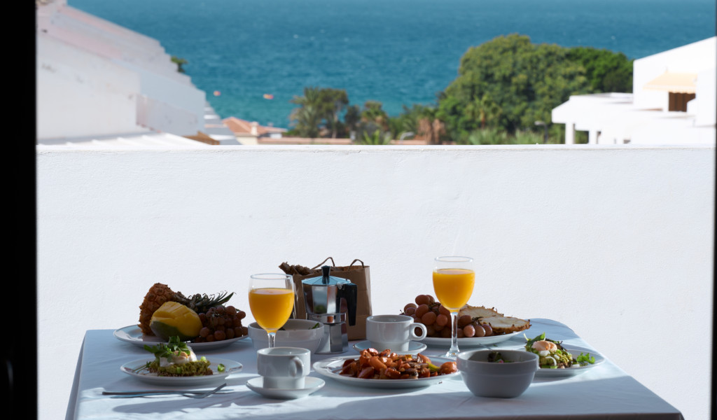 Breakfast table with juice, coffee, fruits, and pastries overlooking the ocean in Tenerife.
