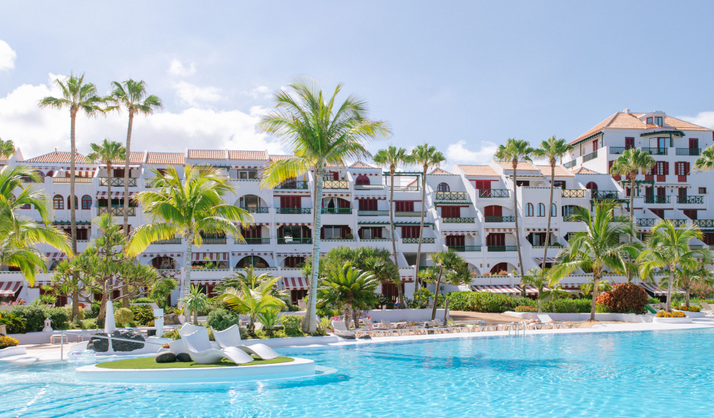 San Eugenio Tenerife resort with palm trees and pool in foreground.