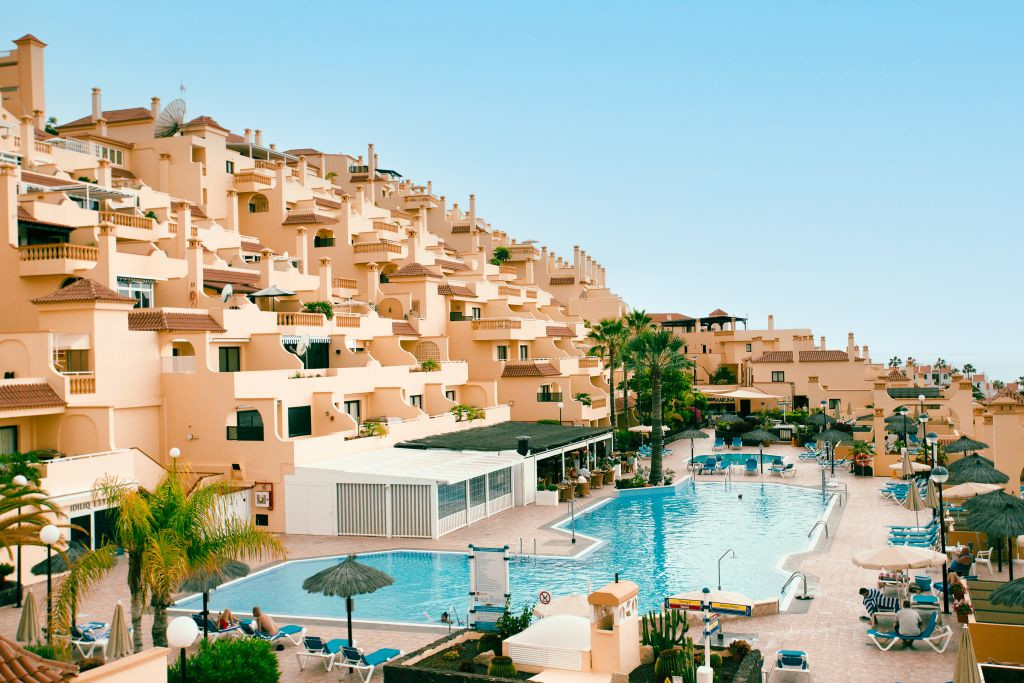 Complex with pool and sunbeds in Tenerife. Palm trees surround the area.