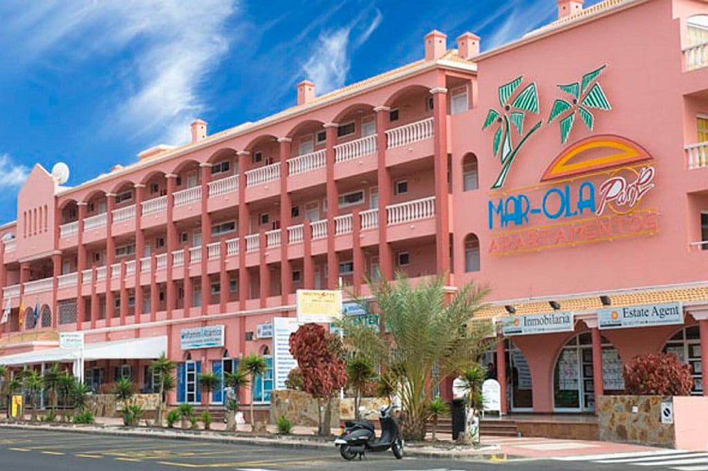 Facade of Mar-Ola Park Apartments in Tenerife with palm trees and blue sky.