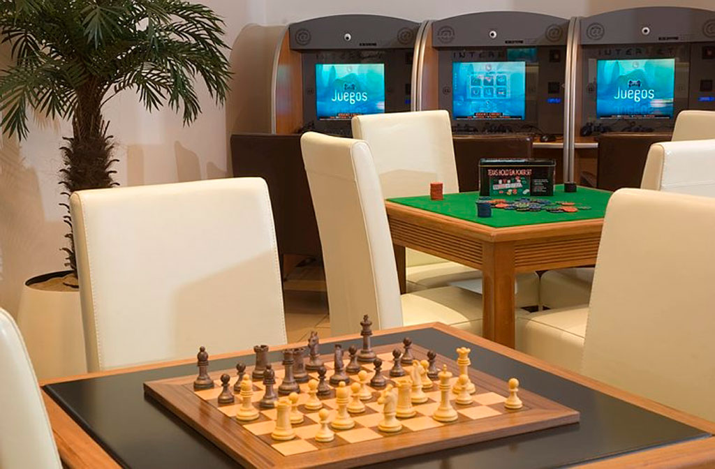 Chessboard and poker table in a gaming room in Tenerife with arcade screens in the background.