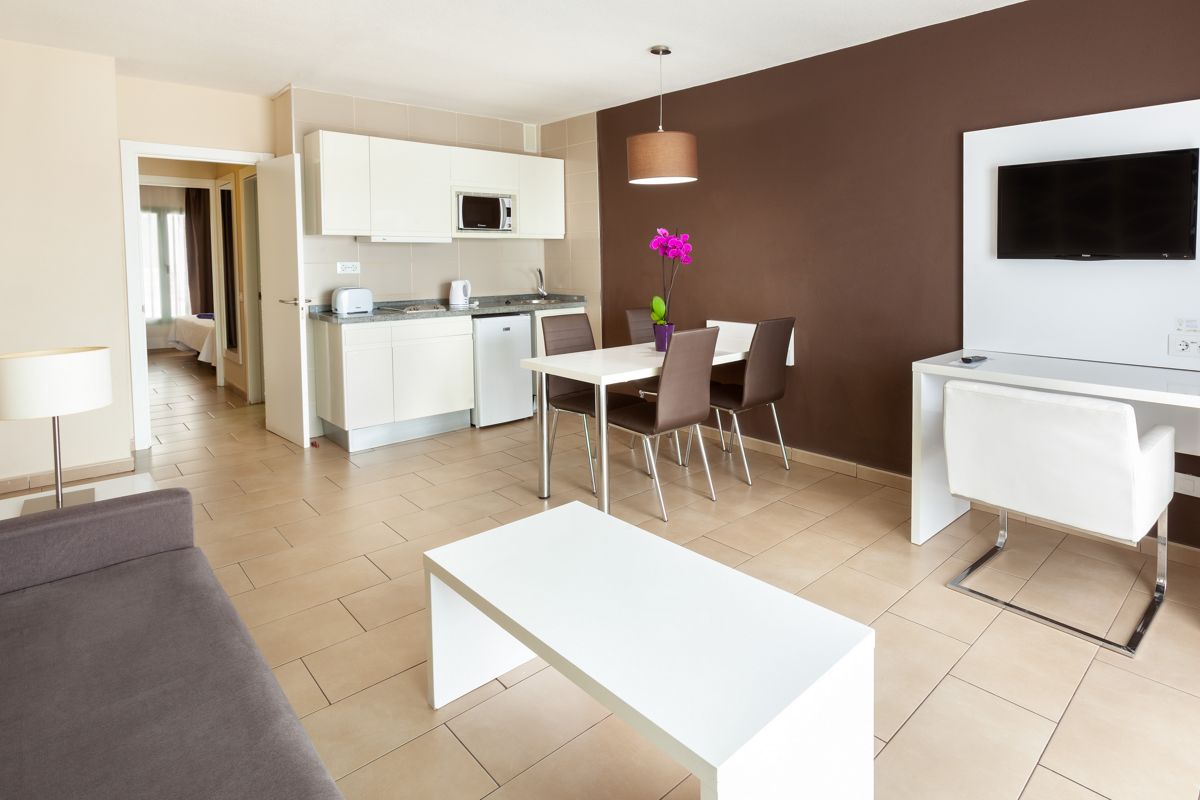 Modern apartment living area with kitchenette, dining table, and sofa in Tenerife.