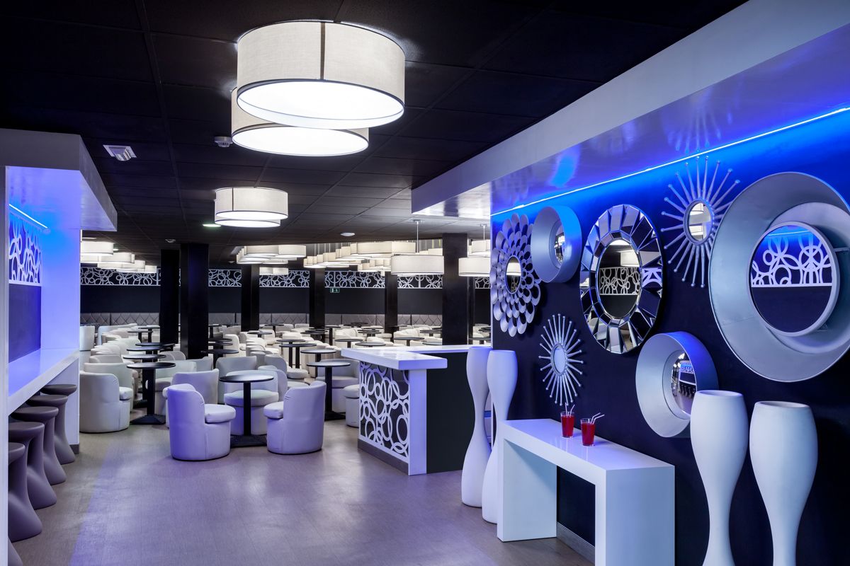 Modern lounge with white chairs and tables, decorative mirrors on wall in Tenerife.