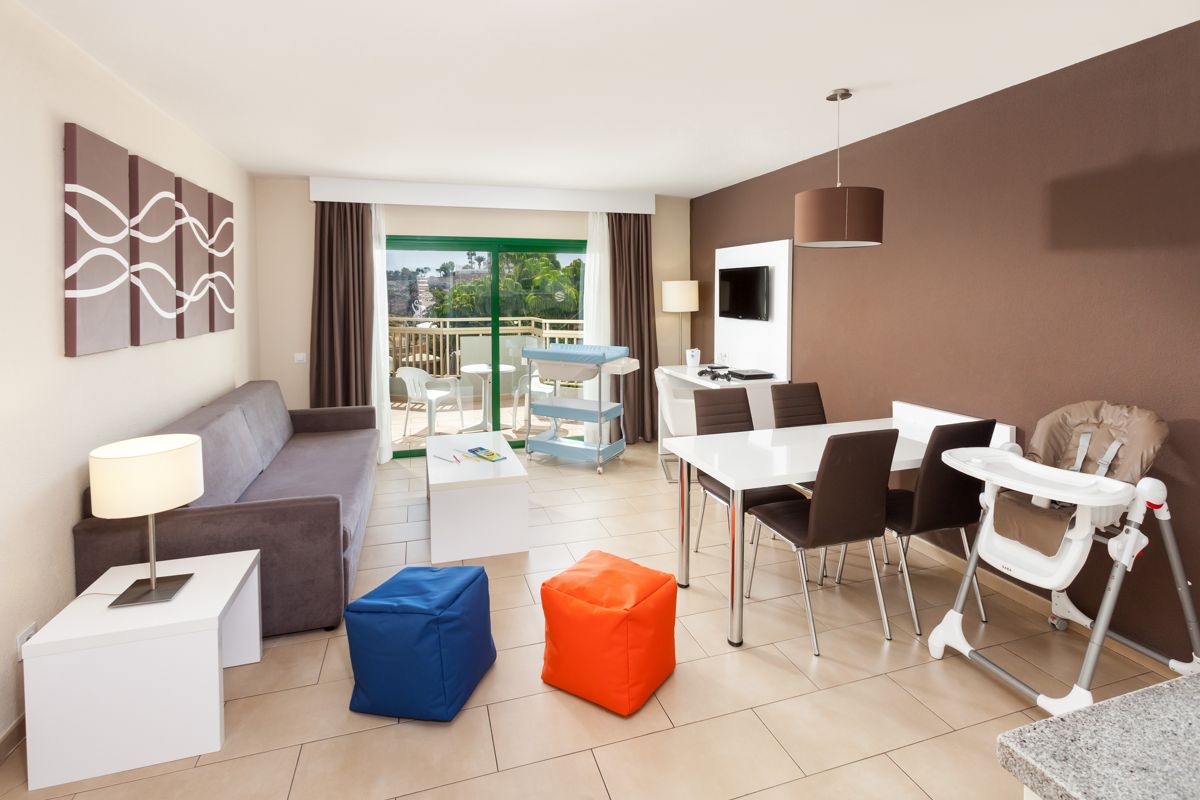 Living room with sofa, dining table, and balcony view in Tenerife apartment.
