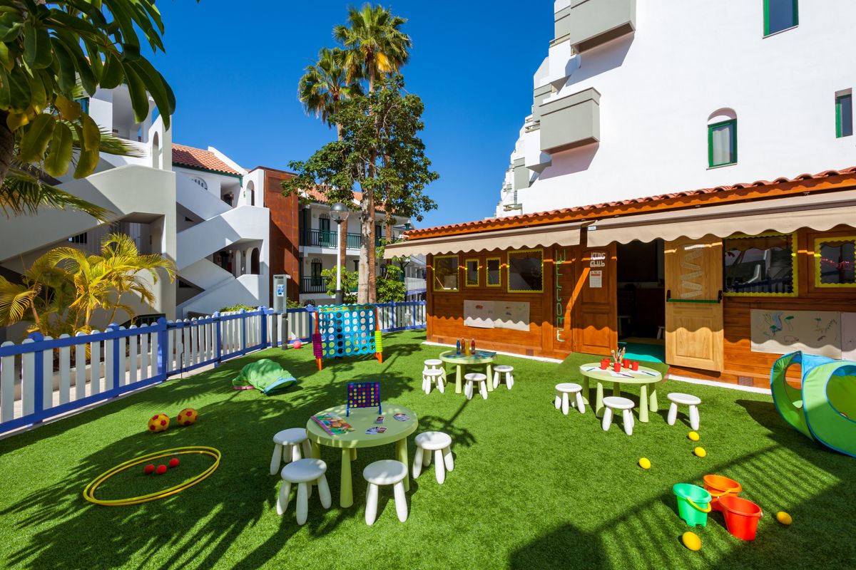 Children's outdoor play area at a Tenerife resort with green tables and small chairs.