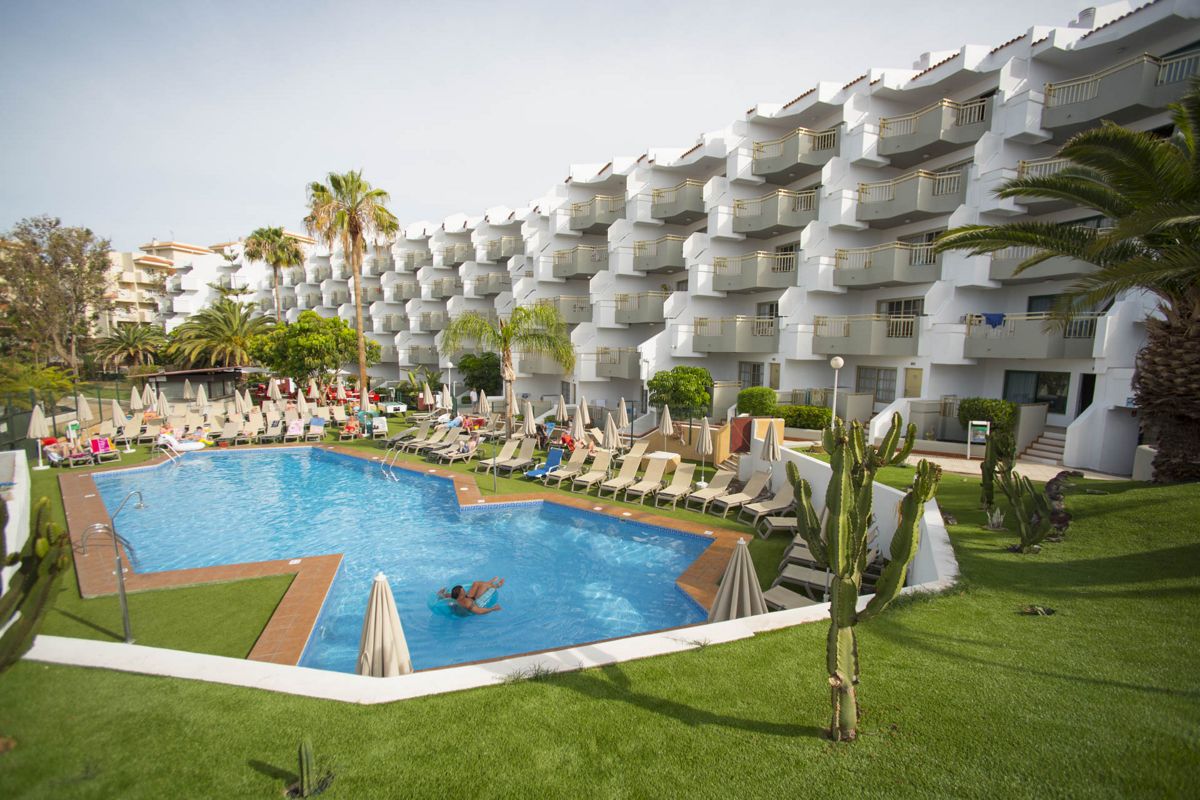 Outdoor pool area with sun loungers and umbrellas at a hotel in Tenerife.