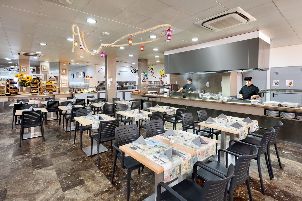 Restaurant interior in Tenerife with chefs cooking behind a counter and tables set for dining.