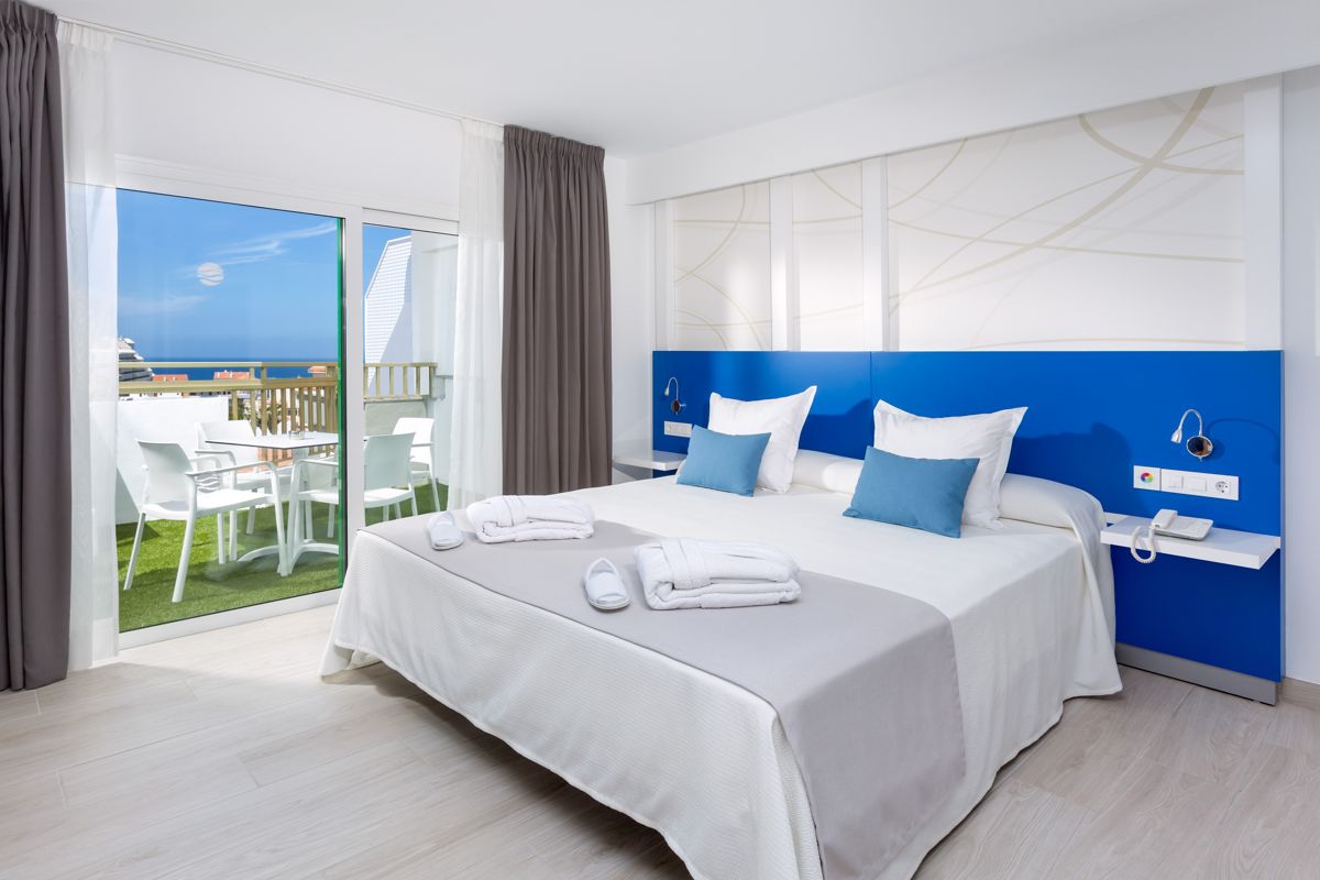 Hotel room in Tenerife with bed, balcony, and ocean view outside the window.