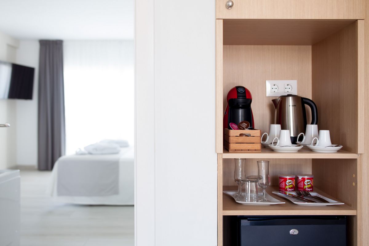 Coffee and tea station in a Tenerife hotel room with cups and a kettle.