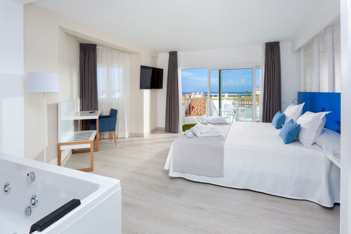 Spacious hotel room in Tenerife with a sea view, bed, and jacuzzi.