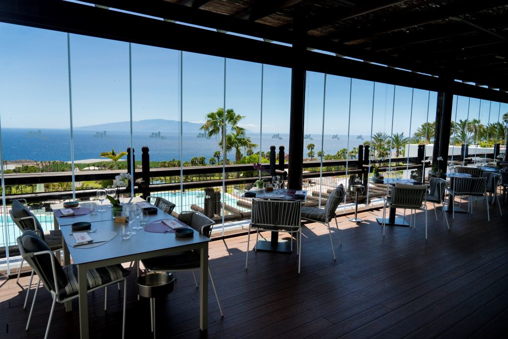 Dining area overlooking the ocean with palm trees in Tenerife.