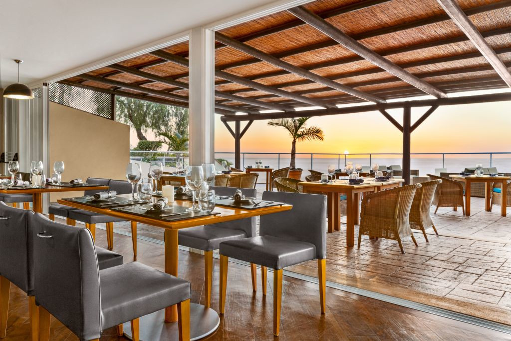 Outdoor dining area with ocean view at sunset in Tenerife restaurant.