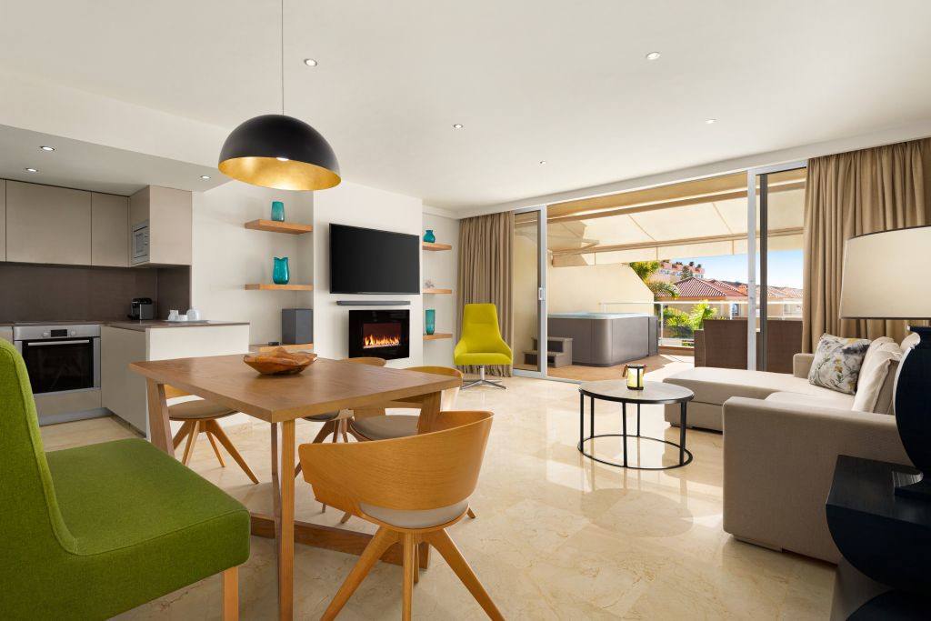 Modern living room with kitchen, patio view, and hot tub in Tenerife.
