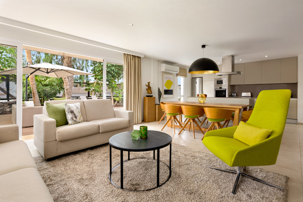 Modern open-plan living room and kitchen with green chair in Tenerife.