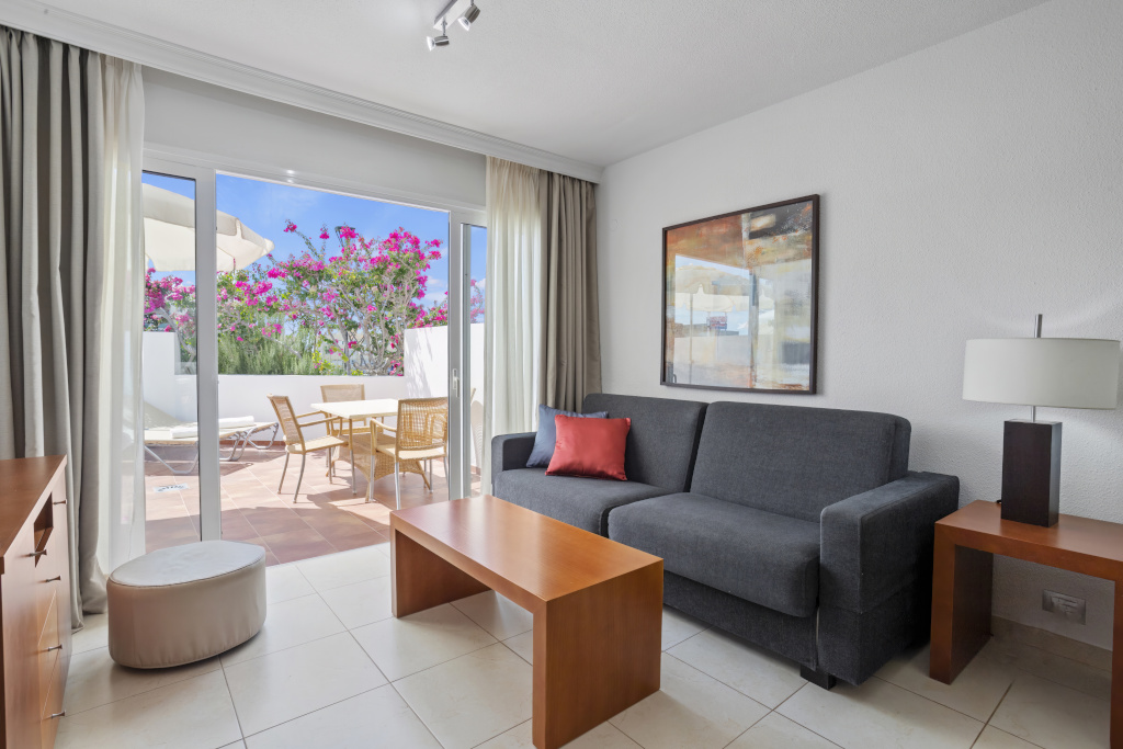 Living room with sofa, table, and terrace view with flowers in Tenerife.