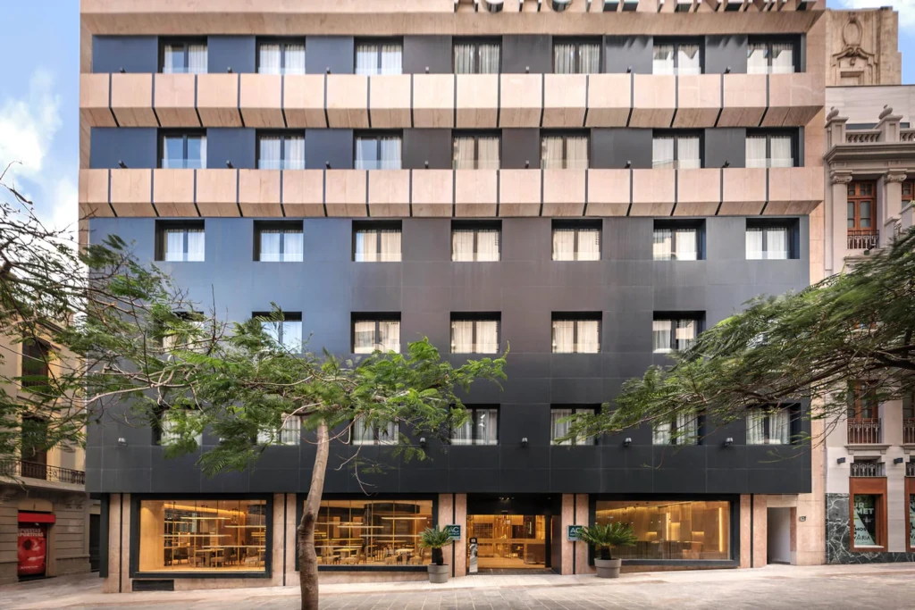 Facade of a modern hotel building in Tenerife with trees in the foreground.